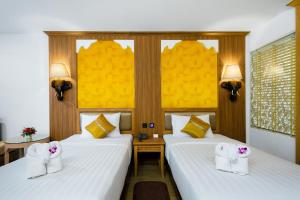 北芭堤雅爱雅拉宫殿酒店的酒店客房,配有两张带白色床单的床