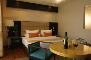 武端市欧厄齐斯酒店的一间卧室配有一张床和一张桌子及一瓶葡萄酒