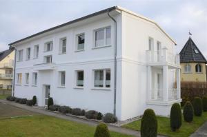 宾茨Villa Herbstwind in Binz的前面有灌木丛的白色房子