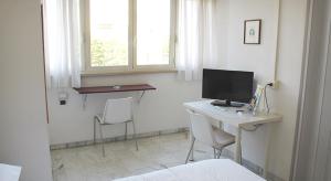安德里亚Albergo dei Pini的客房设有一张桌子、一台电脑和两把椅子