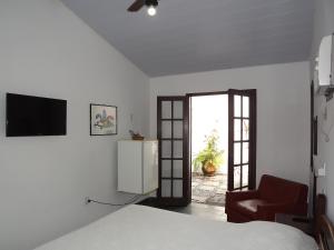 萨夸雷马卡塔温托旅馆 的一间卧室配有一张床、一台电视和一把椅子