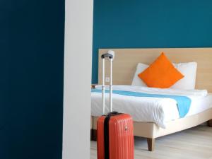 古桑维尔萨格兰姆酒店的酒店客房,配有一张带红色手提箱的床