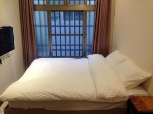 台南开山民宿 的一张带白色床单和枕头的床,位于窗户前