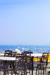 孟买Hotel Harbour View Colaba的一组桌子和椅子,背景是海洋