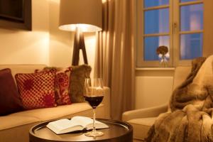 巴特阿罗尔森Hotel Brunnenhaus Schloss Landau的客厅的桌子上放着一杯葡萄酒