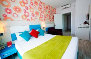 锡德Ramada Resort Side的卧室配有一张带彩色枕头的大型白色床。