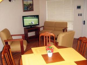 蒙特港Apart Hotel en Puerto Montt的客厅配有桌子和电视