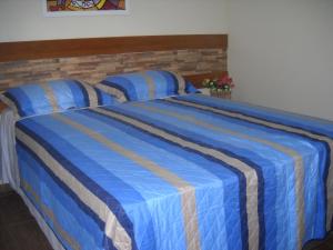 伊瓜苏沙卡拉妈妈盖亚宾馆的蓝色的床和蓝色及棕色条纹毯子