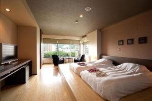 伊东伊东遊季亭日式旅馆的酒店客房设有两张床和一台平面电视。
