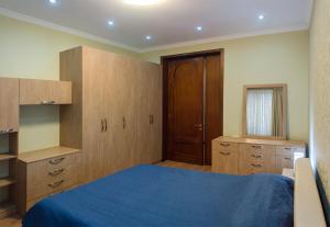 第比利斯Lagidze Apartment的一间卧室配有一张蓝色的床和木制橱柜。