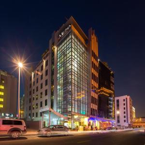 迪拜MENA ApartHotel Albarsha At The Mall的一座高大的建筑,晚上有很多窗户