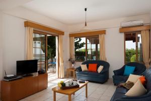 珊瑚湾帕纳乐丽珊瑚湾度假酒店的客厅配有2把蓝色椅子和电视