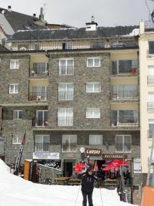 帕斯底拉卡萨夏尔巴马德里乌公寓酒店的滑雪者在建筑物前的雪中