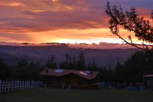 瓦拉斯The Lazy Dog Inn a Mountain Lodge的山丘上的房子,背景是日落