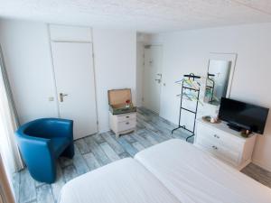 多廷赫姆赫拉夫斯哈普城市酒店的一间卧室配有一张床、一张蓝色椅子和电视