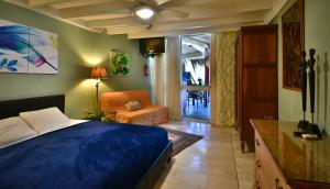棕榈滩Beach House Aruba Apartments的一间卧室配有蓝色的床、椅子和窗户