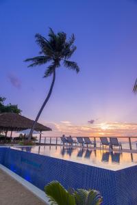 拉迪格岛拉迪格诺迪克海滨酒店的一座带椅子的游泳池,以及毗邻大海的棕榈树