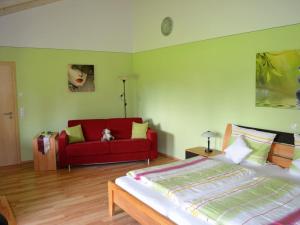 WinzerFerienhof Nirschl的一间卧室配有一张床和一张红色的沙发