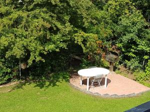 弗里茨拉尔Fritzlar Ederauen的树木繁茂的院子中的白色桌子和椅子