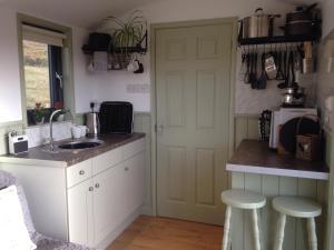 兰德林多德威尔斯Upper Gilwern Quarry Hut的厨房配有水槽和带凳子的台面