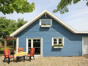 施特芬斯哈根Modern Holiday Home in Steffenshagen with Terrace的蓝色的房子,配有红色的椅子和桌子