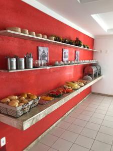瓜拉久巴Pousada Praia De Guarajuba的厨房设有红色的墙壁,配有带食物的书架