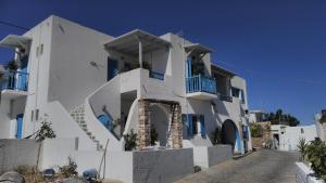 伊拉克利亚岛Angelos Rooms的白色的房子,在街上设有蓝色的阳台