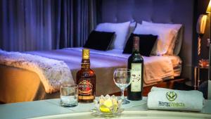 瓦努科Hotel Venecia的桌子上摆放了两瓶葡萄酒和眼镜,配有一张床