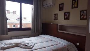 格拉玛多Apartamento Gramado的一间卧室设有一张床和一个大窗户