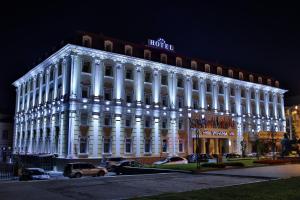 罗夫诺乌克兰罗夫诺酒店 的一座白色的大建筑,晚上有灯