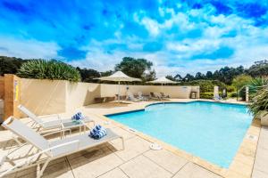 玛格丽特河巴斯尔德内庄园美爵酒店的一个带白色躺椅的游泳池和一个泳池景