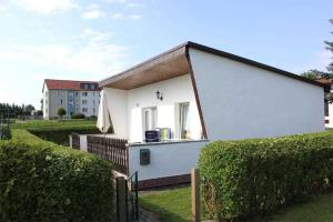 KummerowFerienhaus Kummerow SCHW 731的一座白色的小房子,带有栅栏和灌木