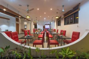 乌库拉斯Paguro Beach Inn的一间餐厅,房间内设有红色的椅子和桌子