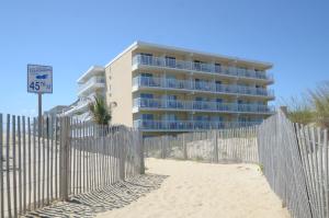 大洋城SeaLoft Oceanfront Hotel的海滩上一座围栏旁的建筑