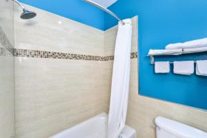 Mission Bend苏格兰南六号公路旅馆及套房的带浴缸和卫生间的浴室以及蓝色的墙壁。