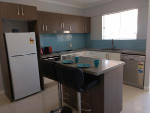 卡伦德拉绿洲私人两床公寓的厨房配有白色冰箱和桌椅