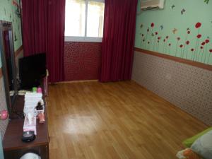 春川集林汽车旅馆的客厅铺有木地板,配有红色窗帘