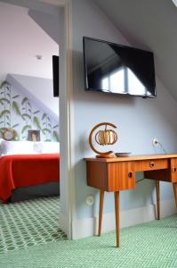 索姆河畔的圣瓦列里勒斯皮勒特斯酒店的卧室配有一张桌子,墙上配有电视