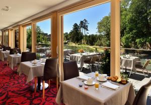 昂西桑多梅因都莫林Spa餐厅酒店的餐厅设有桌椅和大窗户。