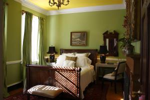 夏洛茨维尔Inn at Court Square的一间卧室配有一张带绿色墙壁的床和一张书桌