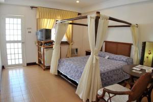 长滩岛Surfside Boracay Resort的一间卧室配有一张床、一张桌子和一台电视