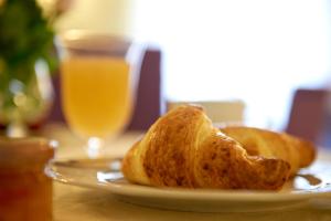 佛罗伦萨佛罗伦萨卡皮塔尔酒店的盘子里的两块面包,加上一杯橙汁