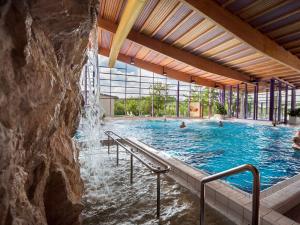 沃尔肯施泰因瓦尔德姆勒餐厅酒店的一座带瀑布的游泳池,里面的人