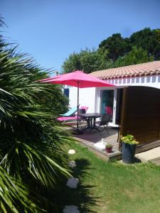 圣吉尔-克鲁瓦德维GÎTE DES FRUCHES的一个带桌子和红色遮阳伞的庭院