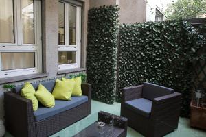 米兰Milano Porta Venezia Suite Centro的庭院设有两把椅子和一张带黄色枕头的沙发。