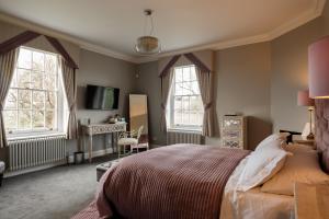 威克福德B&B Downham Hall的一间卧室配有床、两个窗户和一张书桌