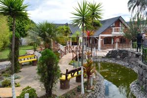 基多Hosteria Quinta Paraiso的一座带池塘、长椅和棕榈树的房子