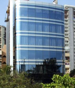 孟买瑞典设计型酒店的一座蓝色玻璃建筑,前面有树木