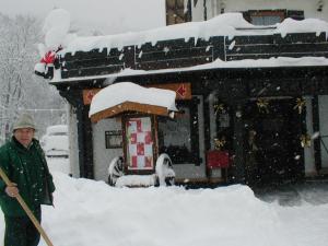 拜尔斯布龙Garni Hotel Adler Post的站在雪地里,用铲子 ⁇ 着一个人