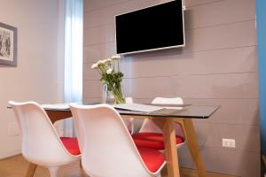 米兰Milano Repubblica Suite Centro的餐桌、白色椅子和墙上的电视